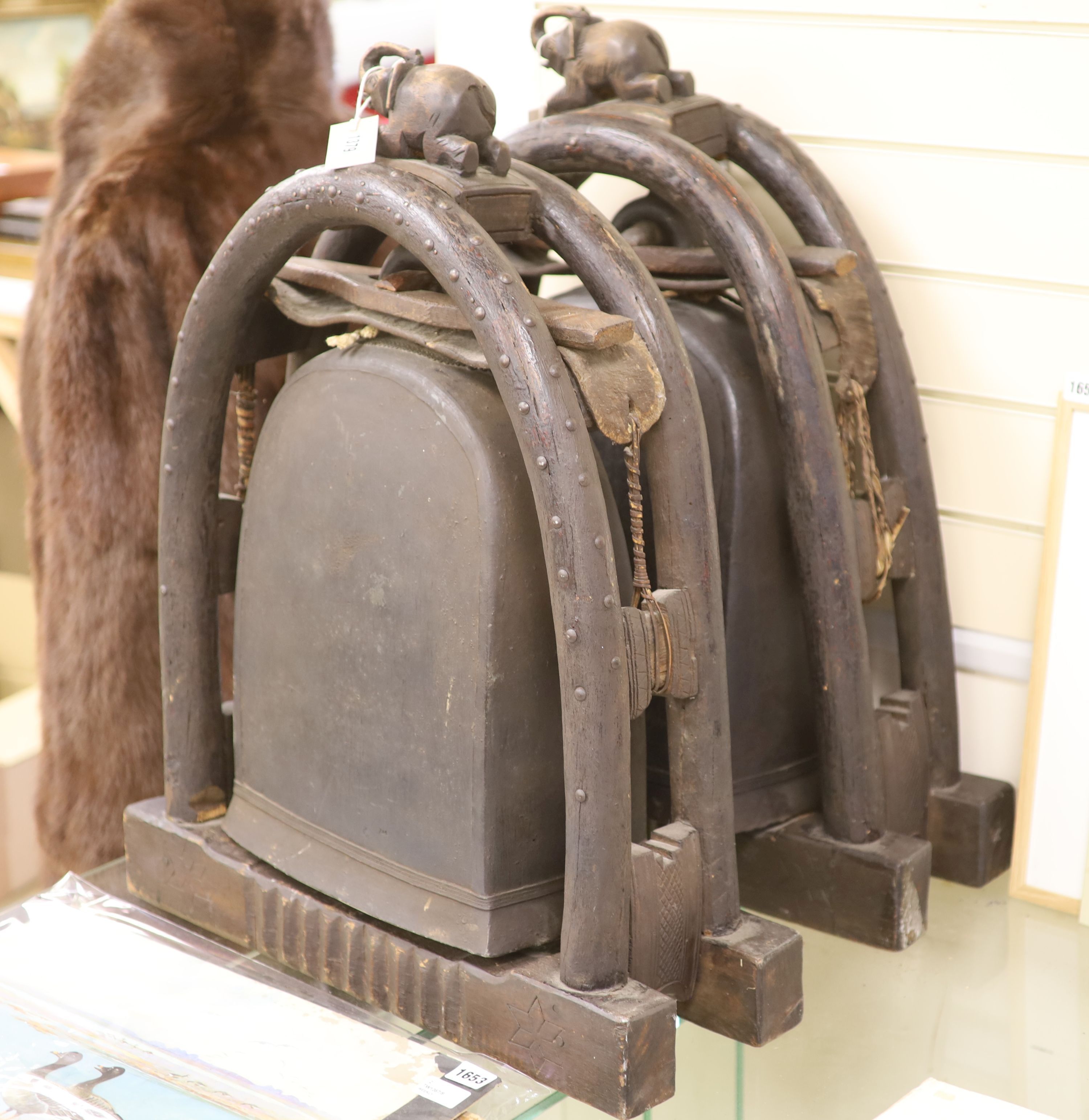 A pair of Eastern bronze elephant bells, each mounted within a carved arched hardwood frame with elephant surmount